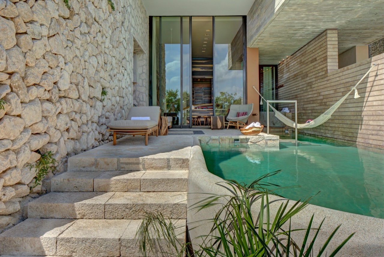 Private plunge pool with a hammock and stone walls in a suite at La Casa de la Playa